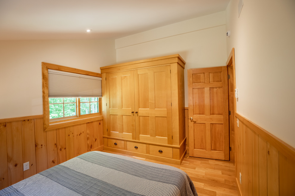 Ejemplo de habitación de invitados rural de tamaño medio sin chimenea con suelo de madera clara, suelo beige, paredes beige, techo inclinado y boiserie