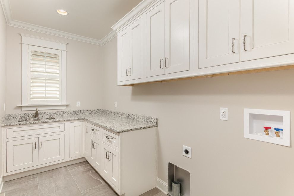 Mid-sized transitional l-shaped porcelain tile dedicated laundry room photo with an undermount sink, recessed-panel cabinets, white cabinets, granite countertops and beige walls