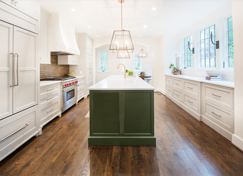 Country galley kitchen in Birmingham with recessed-panel cabinets, green cabinets, brown splashback, brick splashback, panelled appliances, dark hardwood floors, with island, brown floor and white benchtop.