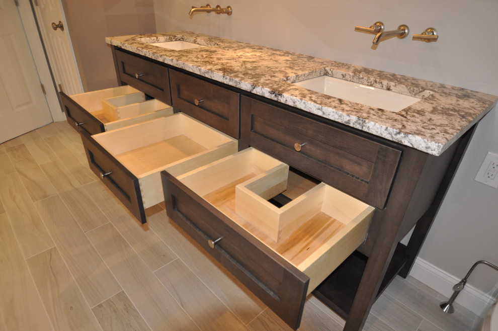 Photo of a modern bathroom in Boston with an undermount sink, furniture-like cabinets, medium wood cabinets, granite benchtops, a freestanding tub, a curbless shower, a two-piece toilet and gray tile.
