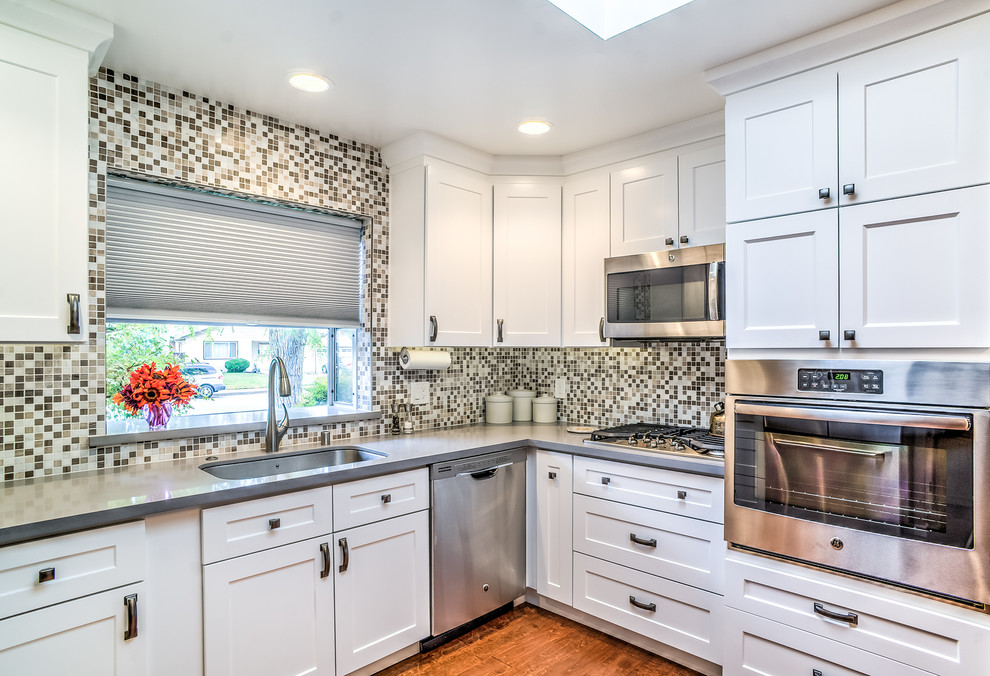 Enclosed kitchen - small transitional u-shaped medium tone wood floor and brown floor enclosed kitchen idea in San Francisco with a single-bowl sink, shaker cabinets, white cabinets, quartz countertops, multicolored backsplash, stainless steel appliances, no island and mosaic tile backsplash