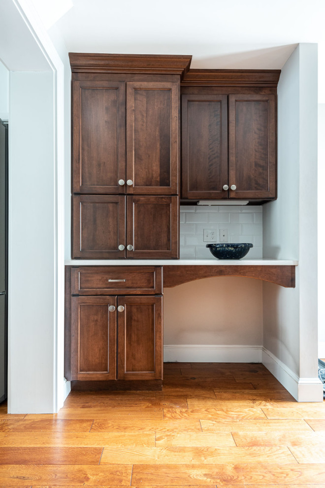 Example of a large transitional l-shaped medium tone wood floor and brown floor eat-in kitchen design in Boston with an undermount sink, shaker cabinets, white cabinets, quartz countertops, white backsplash, subway tile backsplash, stainless steel appliances, an island and white countertops