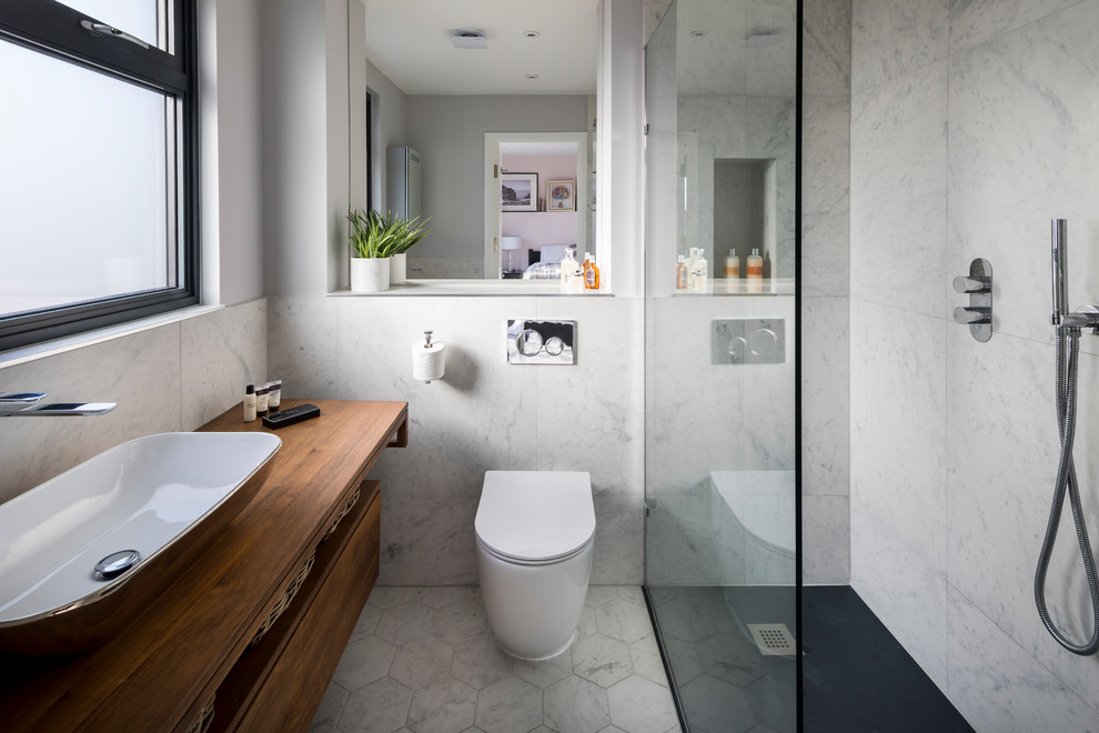 Photo of a small contemporary 3/4 bathroom in London with a corner shower, a one-piece toilet, gray tile, marble, grey walls, linoleum floors, a trough sink, wood benchtops, white floor, an open shower, flat-panel cabinets, medium wood cabinets and brown benchtops.