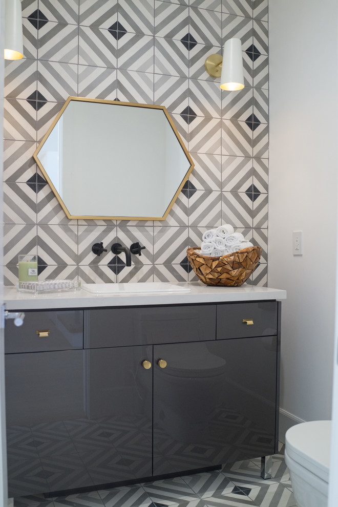 Photo of a mid-sized contemporary powder room in Orange County with flat-panel cabinets, grey cabinets, a one-piece toilet, gray tile, cement tile, white walls, a drop-in sink and engineered quartz benchtops.