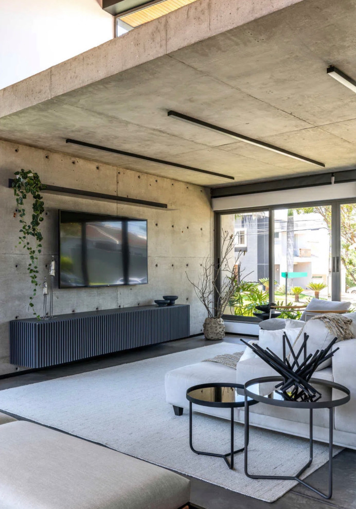 Modern inredning av ett stort allrum med öppen planlösning, med grå väggar, betonggolv, en inbyggd mediavägg och grått golv