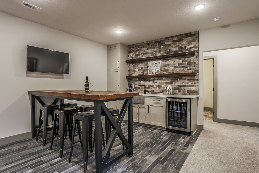 This is an example of a modern seated home bar in Omaha with shaker cabinets, wood benchtops, brick splashback and porcelain floors.
