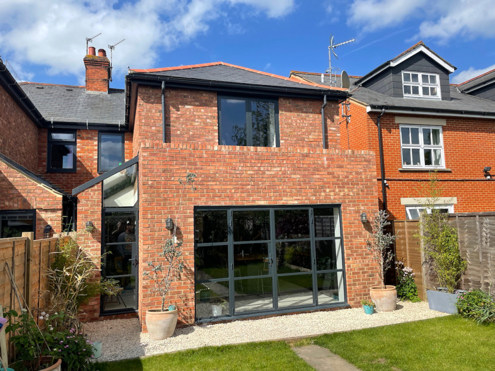 Photo of a medium sized and red contemporary two floor brick and rear house exterior in Berkshire with a pitched roof, a tiled roof and a grey roof.