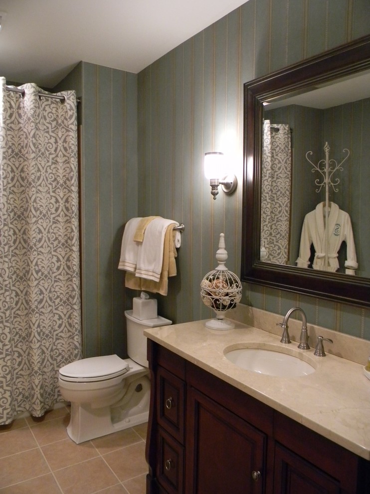 Tub/shower combo - mid-sized transitional brown tile and porcelain tile porcelain tile tub/shower combo idea in DC Metro with an undermount sink, raised-panel cabinets, dark wood cabinets, marble countertops, a two-piece toilet and blue walls