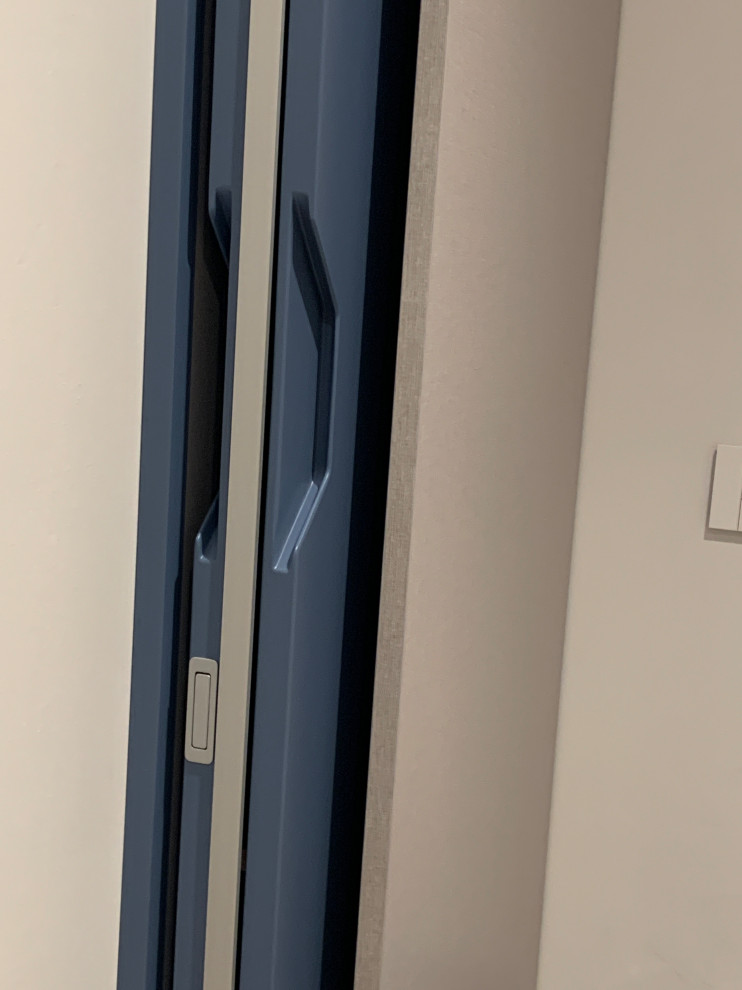 Cette image montre une buanderie linéaire design dédiée avec un évier utilitaire, un placard à porte persienne, des portes de placard bleues, un mur bleu, un sol en carrelage de porcelaine, des machines superposées, un sol gris et du papier peint.