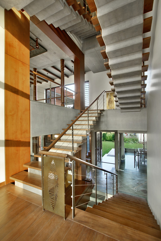 Asian wood u-shaped staircase in Ahmedabad with concrete risers and cable railing.