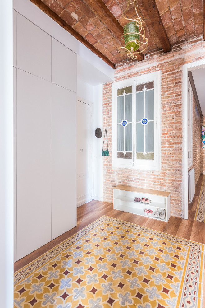 Mittelgroße Klassische Haustür mit weißer Wandfarbe, Vinylboden, Einzeltür, weißer Haustür, buntem Boden, freigelegten Dachbalken und Ziegelwänden in Barcelona