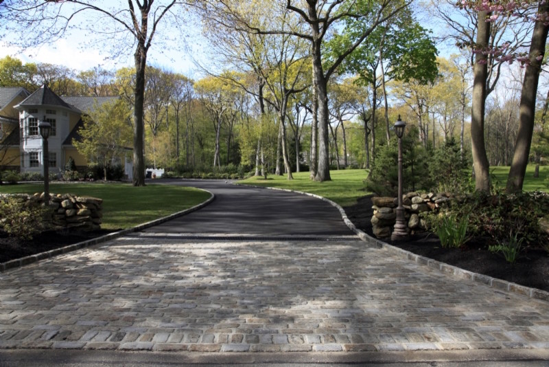 Expansive traditional front yard shaded driveway in New York with natural stone pavers.
