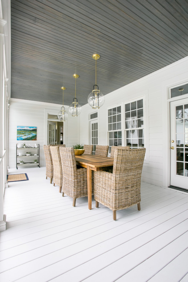 This is an example of a large coastal screened-in back porch design in Charleston with a roof extension.