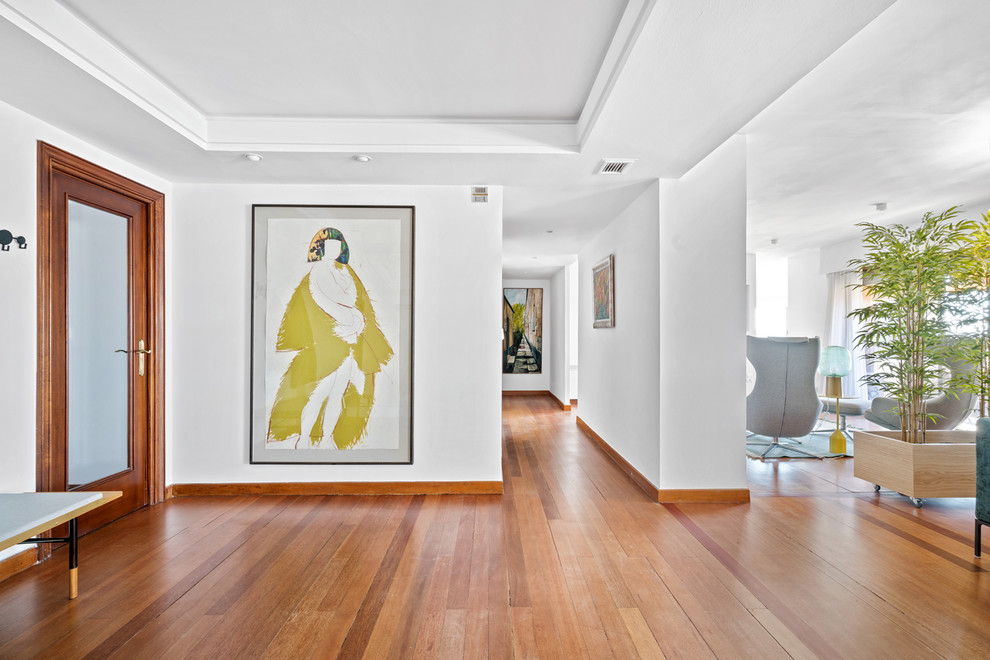 This is an example of a large contemporary foyer in Other with white walls, medium hardwood floors, brown floor, a single front door and a glass front door.
