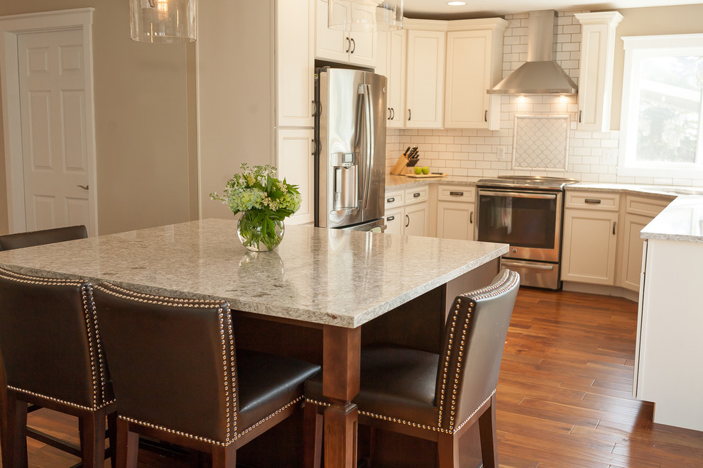 Inspiration for a mid-sized transitional u-shaped dark wood floor open concept kitchen remodel with an undermount sink, raised-panel cabinets, white cabinets, quartzite countertops, white backsplash, subway tile backsplash, stainless steel appliances and an island