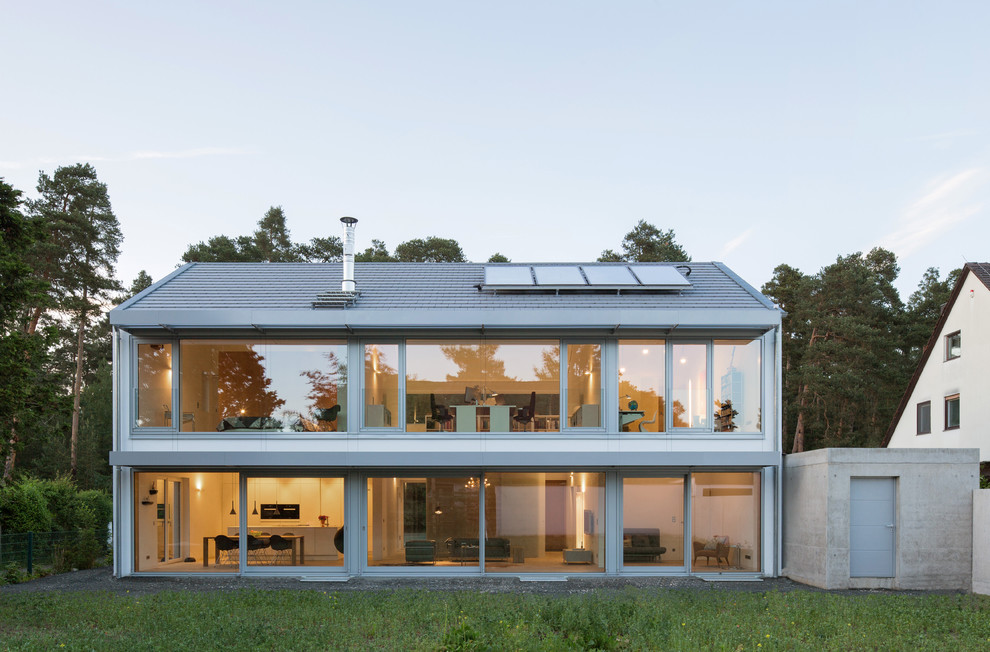 Design ideas for a mid-sized contemporary two-storey glass white house exterior in Munich with a gable roof.