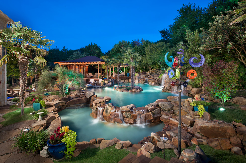 Photo of an expansive tropical backyard custom-shaped natural pool in Dallas with a water slide and stamped concrete.