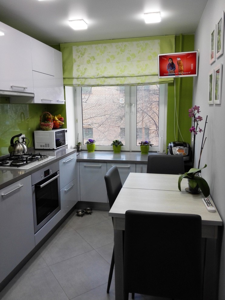 Small contemporary l-shaped separate kitchen in Moscow with a single-bowl sink, flat-panel cabinets, grey cabinets, laminate benchtops, green splashback, glass sheet splashback, stainless steel appliances, porcelain floors, no island and grey floor.