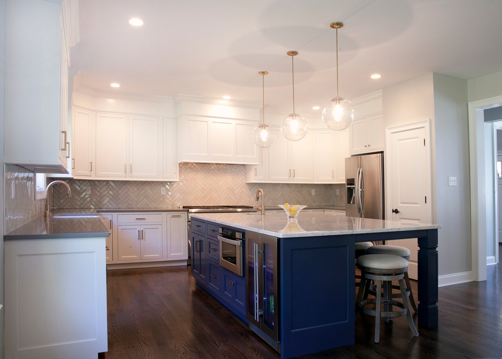 Design ideas for a large transitional u-shaped open plan kitchen in Philadelphia with a farmhouse sink, shaker cabinets, white cabinets, marble benchtops, white splashback, porcelain splashback, stainless steel appliances, dark hardwood floors and with island.