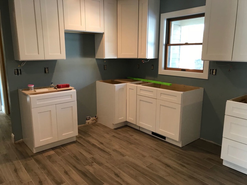 Example of a huge minimalist l-shaped kitchen pantry design with shaker cabinets and white cabinets