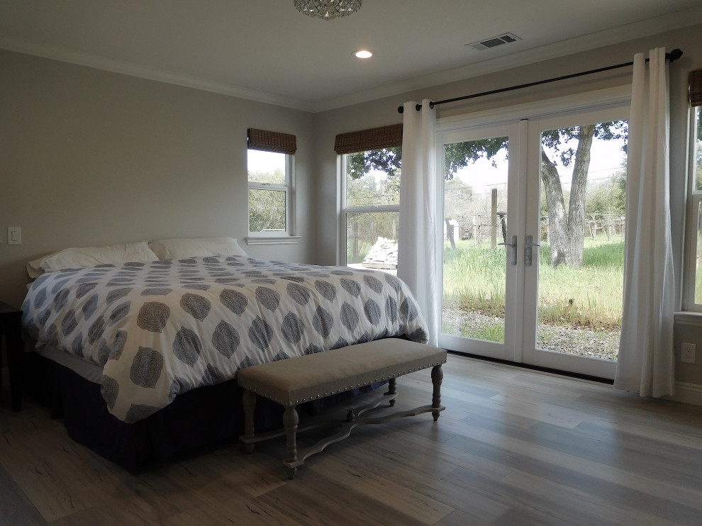 Großes Country Hauptschlafzimmer mit grauer Wandfarbe, Laminat, Kamin, Kaminumrandung aus gestapelten Steinen und grauem Boden in Santa Barbara