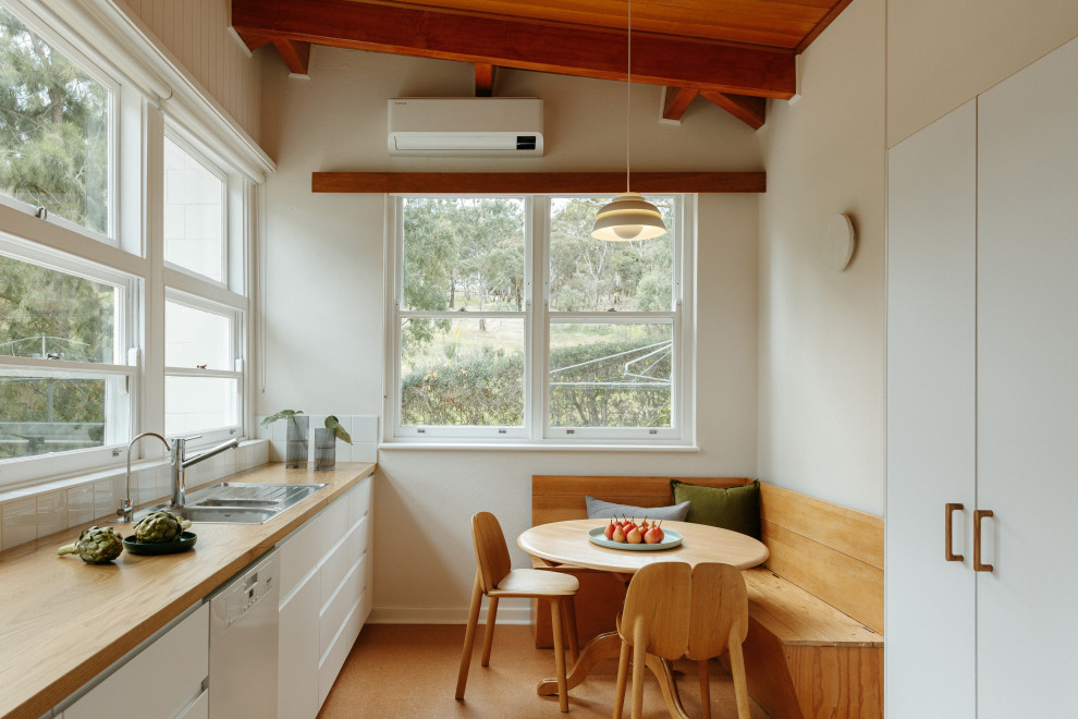 Design ideas for a mid-sized midcentury eat-in kitchen in Adelaide with white cabinets, wood benchtops, white splashback, stainless steel appliances, cork floors, no island, brown floor, brown benchtop and timber.
