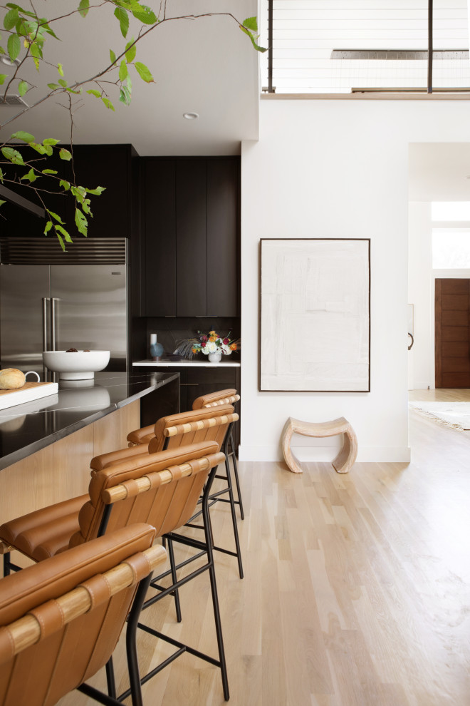 Trendy kitchen photo in Dallas with flat-panel cabinets, black cabinets, quartzite countertops, black backsplash, ceramic backsplash, an island and white countertops