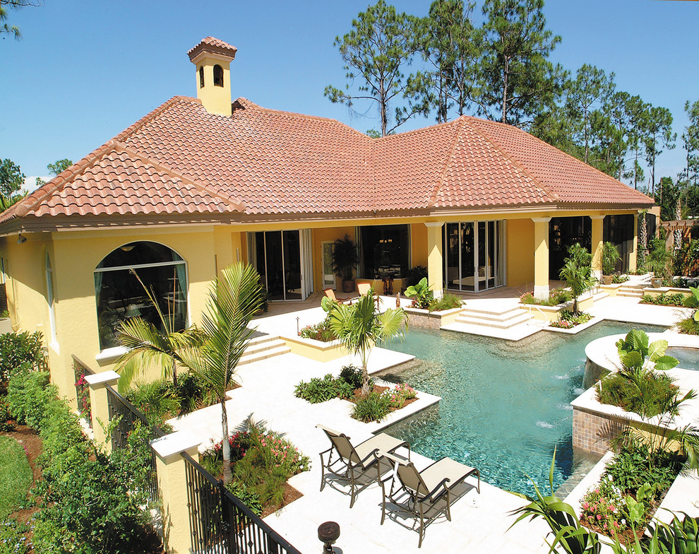 Expansive mediterranean backyard patio in Miami with a water feature, natural stone pavers and a roof extension.
