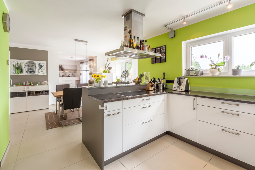 Photo of a mid-sized contemporary l-shaped open plan kitchen in Other with flat-panel cabinets, white cabinets, green splashback, a peninsula, beige floor and black benchtop.