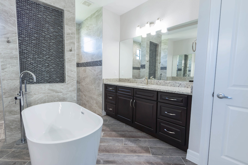 Inspiration for a large traditional master bathroom in Other with raised-panel cabinets, brown cabinets, a freestanding tub, an open shower, grey walls, ceramic floors, an undermount sink, granite benchtops, brown floor and a shower curtain.