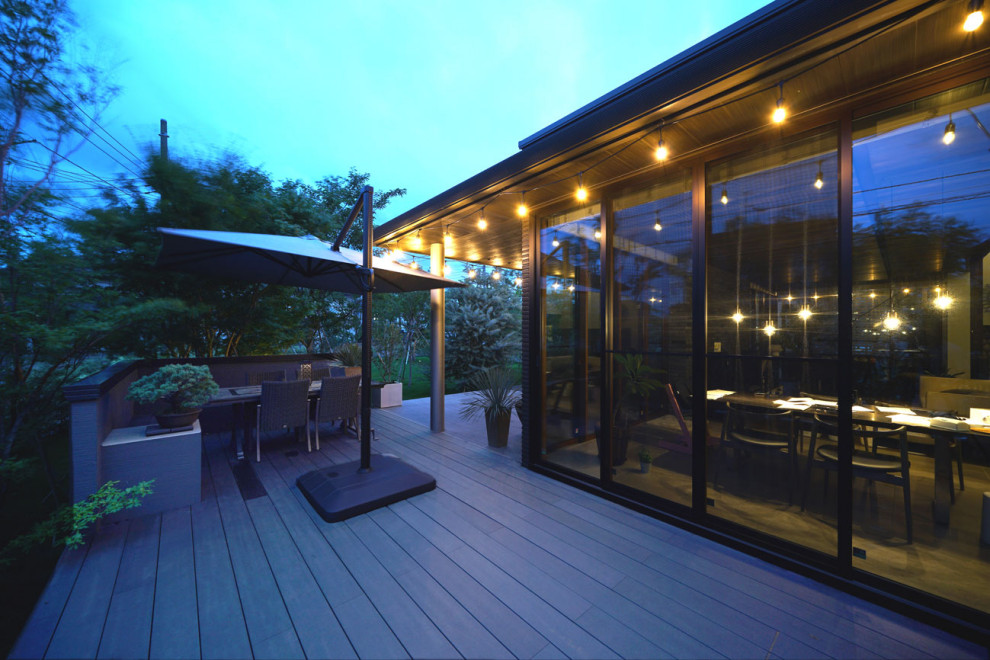 This is an example of an expansive modern side ground level terrace in Other with an outdoor kitchen and an awning.