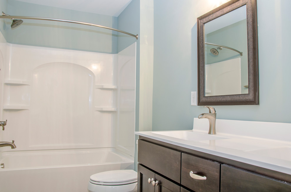 Mid-sized arts and crafts kids bathroom in Richmond with flat-panel cabinets, brown cabinets, an alcove tub, a shower/bathtub combo, a two-piece toilet, blue walls, ceramic floors, an integrated sink, laminate benchtops, brown floor and a shower curtain.
