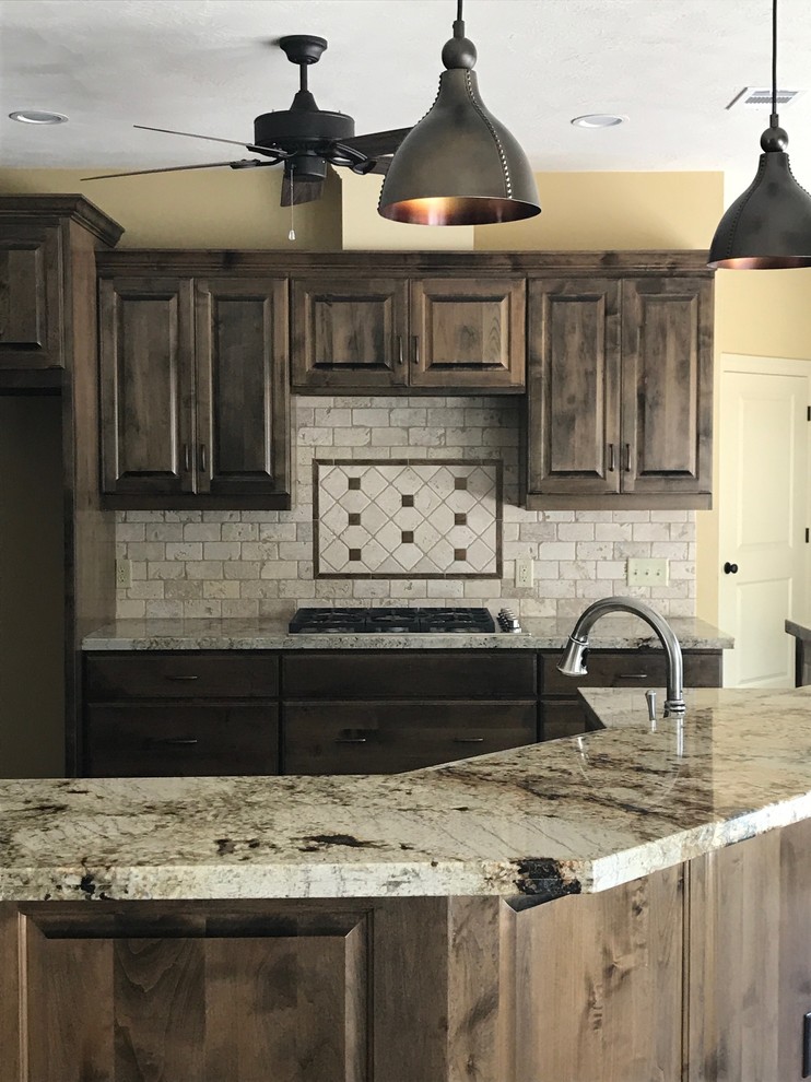 Inspiration for a mid-sized rustic l-shaped open concept kitchen remodel in Austin with raised-panel cabinets, dark wood cabinets, granite countertops, gray backsplash, stone tile backsplash and an island