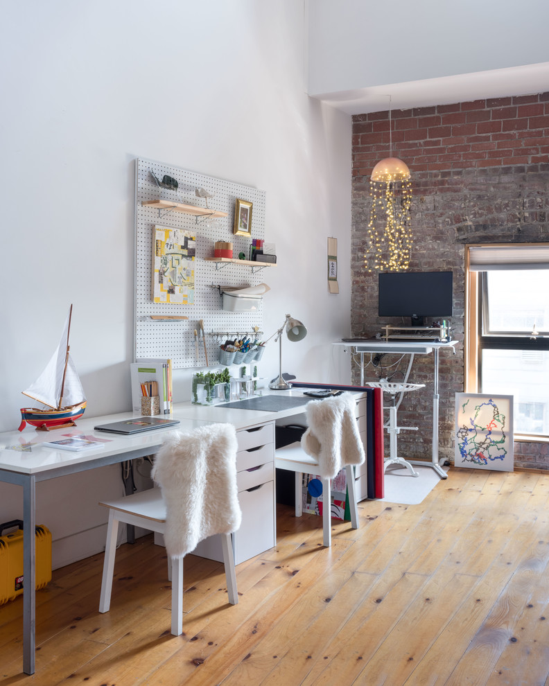 Scandinavian home office in New York with white walls, light hardwood floors, a freestanding desk and beige floor.