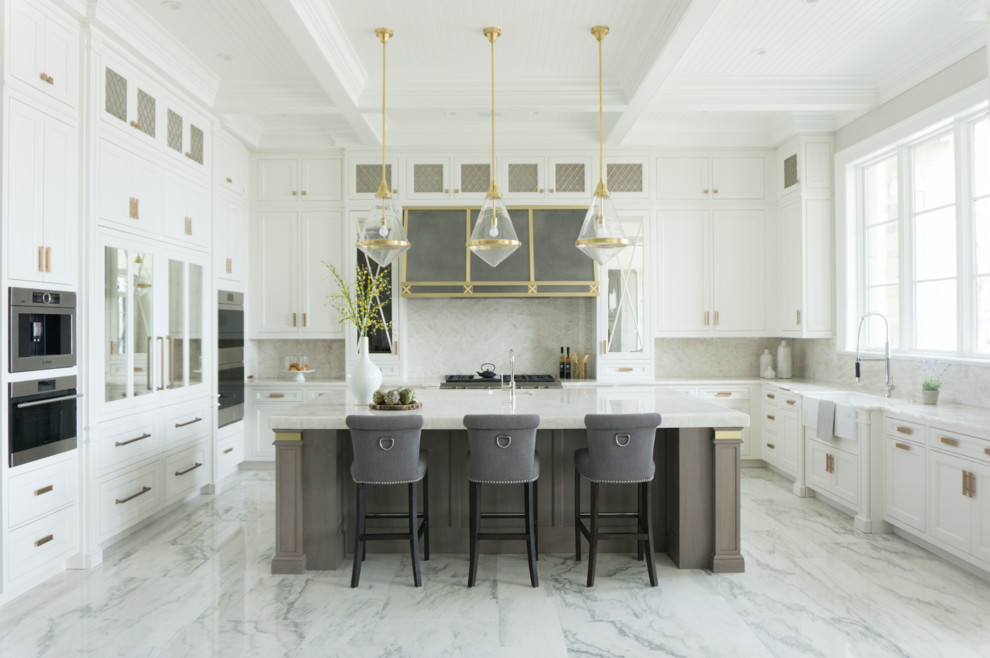 This is an example of an expansive transitional u-shaped eat-in kitchen in Chicago with a farmhouse sink, recessed-panel cabinets, white cabinets, quartzite benchtops, white splashback, stone slab splashback, panelled appliances, marble floors, with island, white floor and white benchtop.