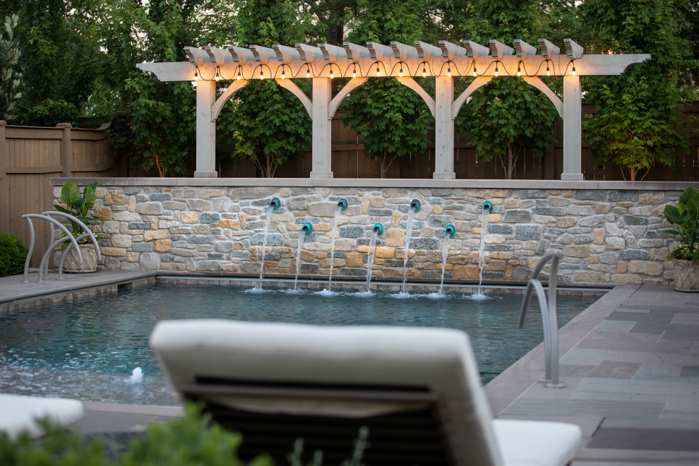 Large transitional backyard stone and rectangular pool fountain photo in Chicago