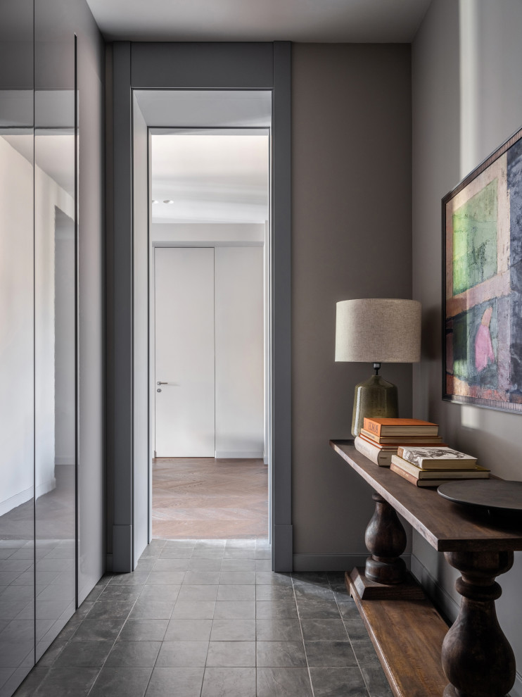 Réalisation d'une grande entrée design avec un couloir, un mur gris, un sol en carrelage de porcelaine, une porte simple, une porte grise et un sol noir.