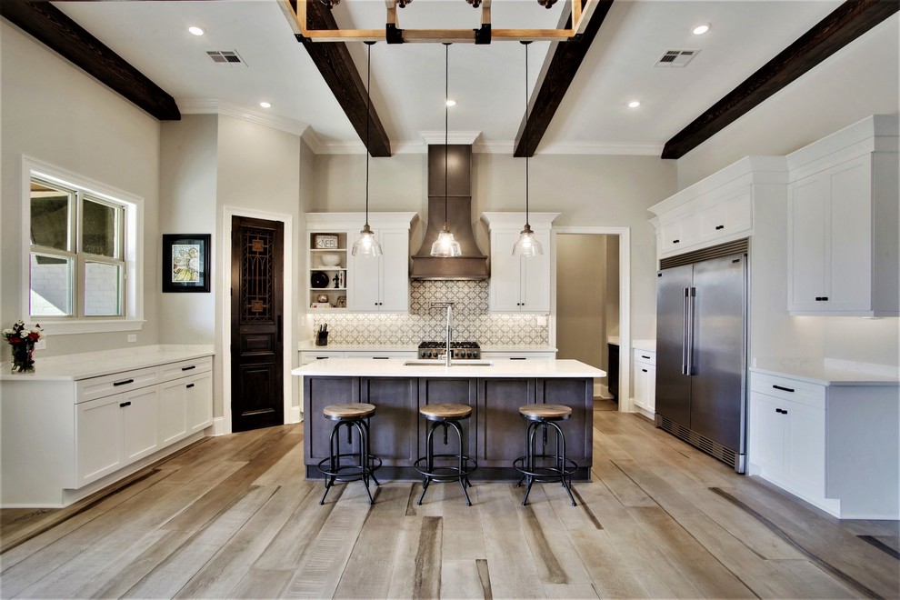 Inspiration for a transitional u-shaped kitchen in New Orleans with an undermount sink, shaker cabinets, white cabinets, grey splashback, stainless steel appliances, light hardwood floors, with island, beige floor and white benchtop.