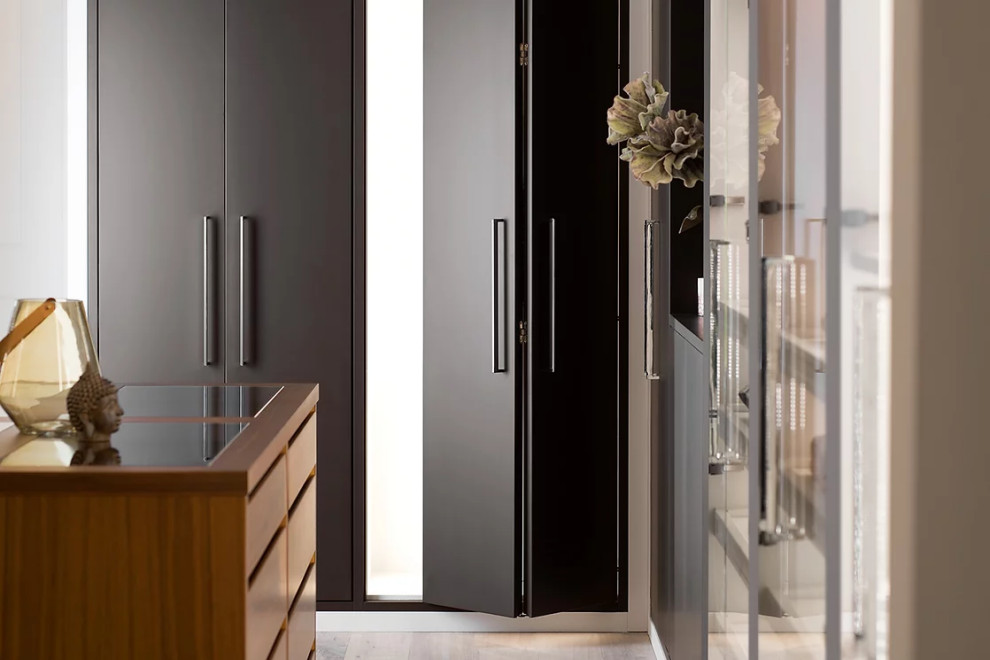 Mid-sized modern gender-neutral walk-in wardrobe in New York with beaded inset cabinets, white cabinets, light hardwood floors, white floor and wood.