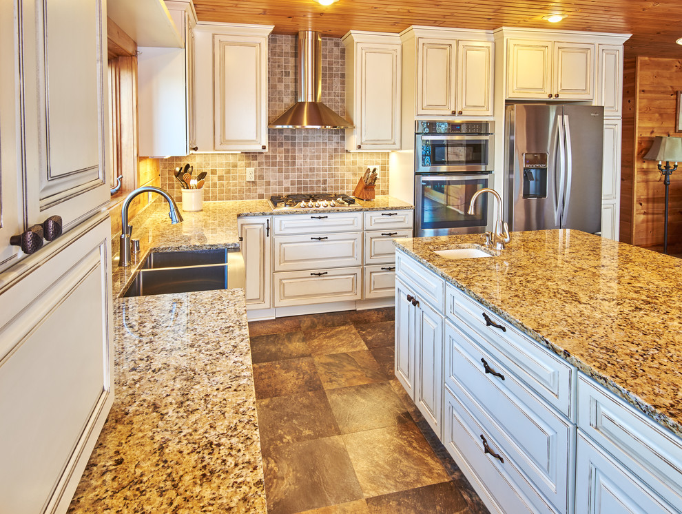 Inspiration for a l-shaped kitchen remodel with a farmhouse sink, distressed cabinets, granite countertops, ceramic backsplash, stainless steel appliances and an island