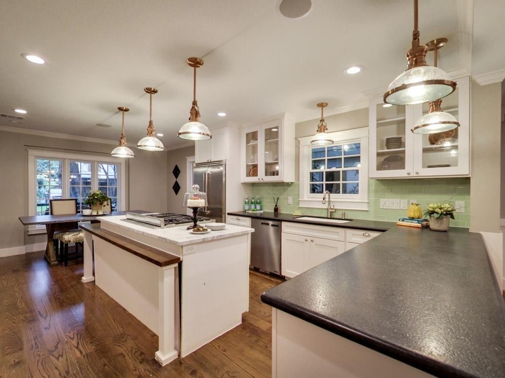 Mid-sized transitional l-shaped medium tone wood floor and brown floor eat-in kitchen photo with an undermount sink, glass-front cabinets, white cabinets, solid surface countertops, green backsplash, subway tile backsplash, stainless steel appliances and an island