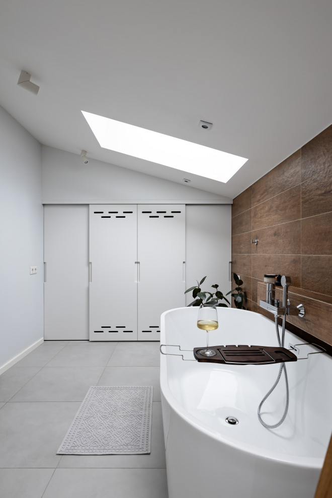 Свежая идея для дизайна: ванная комната среднего размера, в белых тонах с отделкой деревом в скандинавском стиле с отдельно стоящей ванной, коричневой плиткой, керамогранитной плиткой, полом из керамогранита и серым полом - отличное фото интерьера
