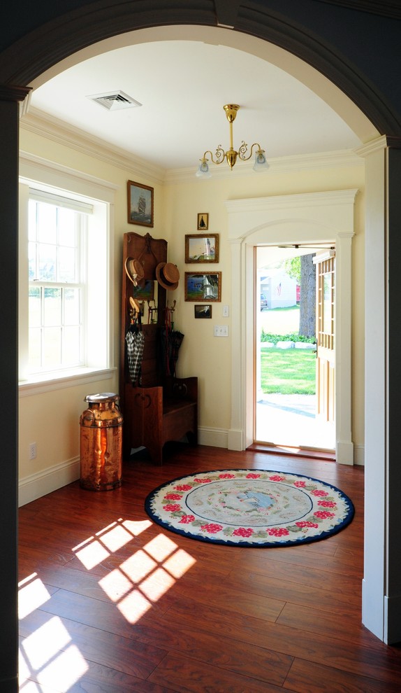 Large traditional foyer in Portland Maine with yellow walls, dark hardwood floors, a single front door and a light wood front door.