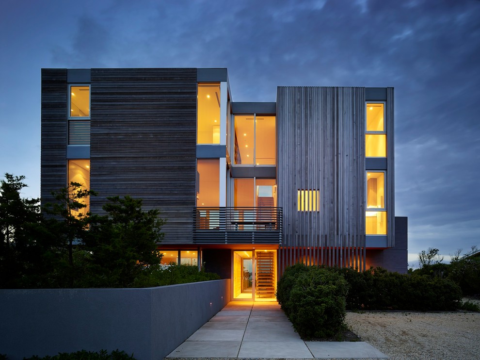 This is an example of a large modern three-storey brown exterior in New York with wood siding and a flat roof.