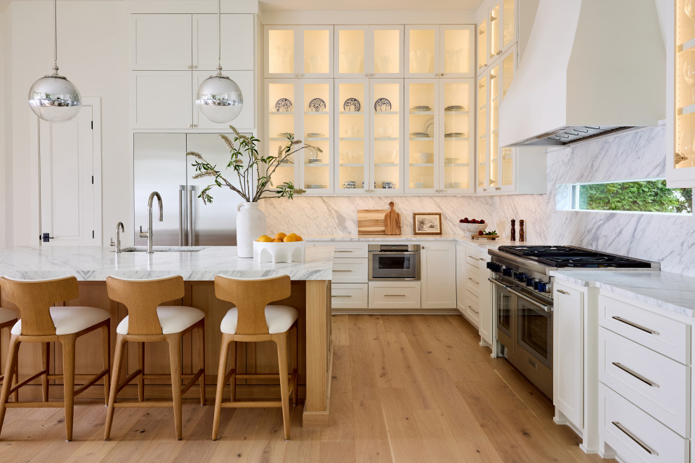 Example of a transitional l-shaped open concept kitchen design in Dallas with shaker cabinets, marble countertops, white backsplash, marble backsplash, stainless steel appliances, an island and white countertops