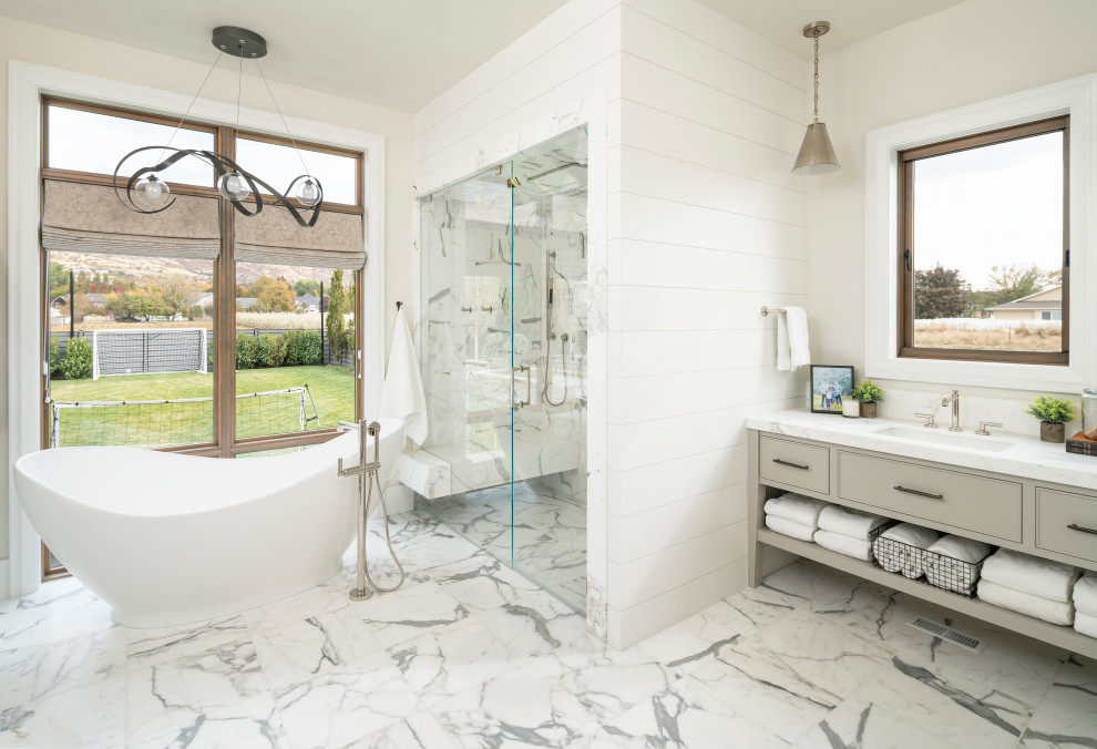 Photo of an expansive country master bathroom in Salt Lake City with beaded inset cabinets, a freestanding tub, a curbless shower, white tile, marble, white walls, marble floors, an undermount sink, engineered quartz benchtops, white floor, a hinged shower door, white benchtops and grey cabinets.