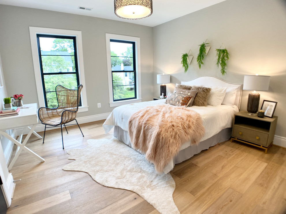Modelo de habitación de bebé neutra de estilo de casa de campo grande con paredes grises, suelo de madera clara y suelo beige