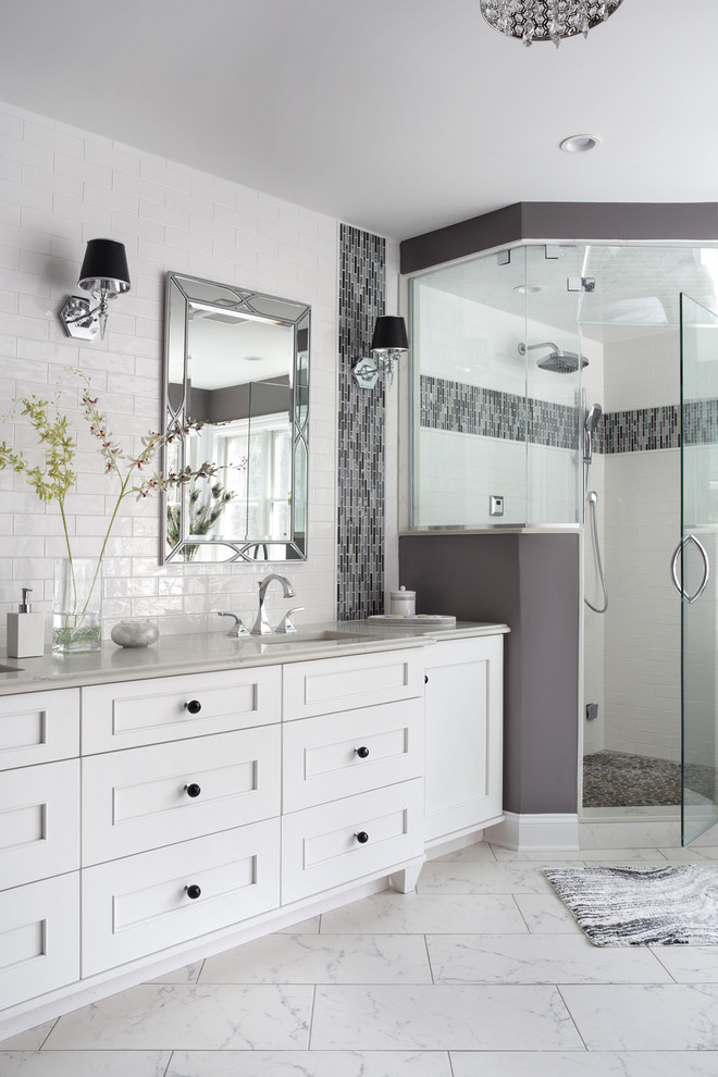 Large transitional master bathroom in New York with recessed-panel cabinets, white cabinets, a freestanding tub, a corner shower, a one-piece toilet, white tile, glass tile, purple walls, porcelain floors, an undermount sink, engineered quartz benchtops, white floor, a hinged shower door and white benchtops.
