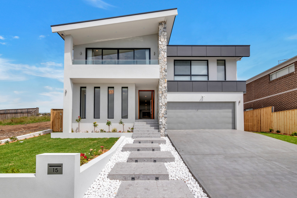 Réalisation d'une grande façade de maison de ville grise minimaliste en pierre de plain-pied avec un toit en métal.