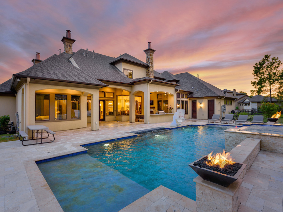 Photo of a large transitional backyard rectangular natural pool in Houston with a hot tub and natural stone pavers.